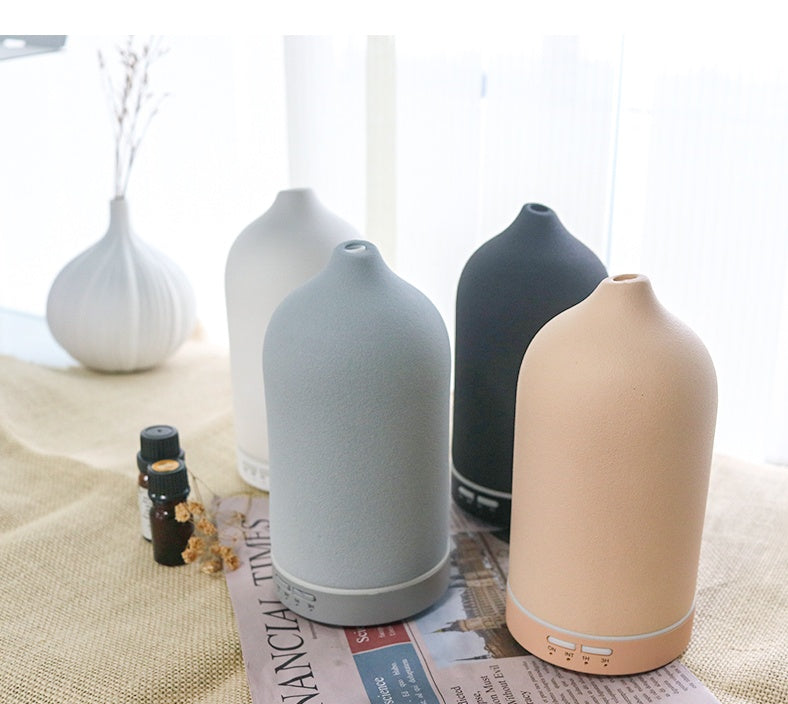 Set of four ceramic diffusers in different colors on a table with a newspaper underneath.